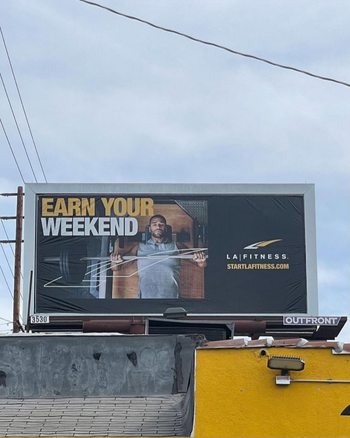 LA Fitness Billboard featuring an image by Caleb Kuhl of an african american man with a focused expression preparing to bench press weights in a gym