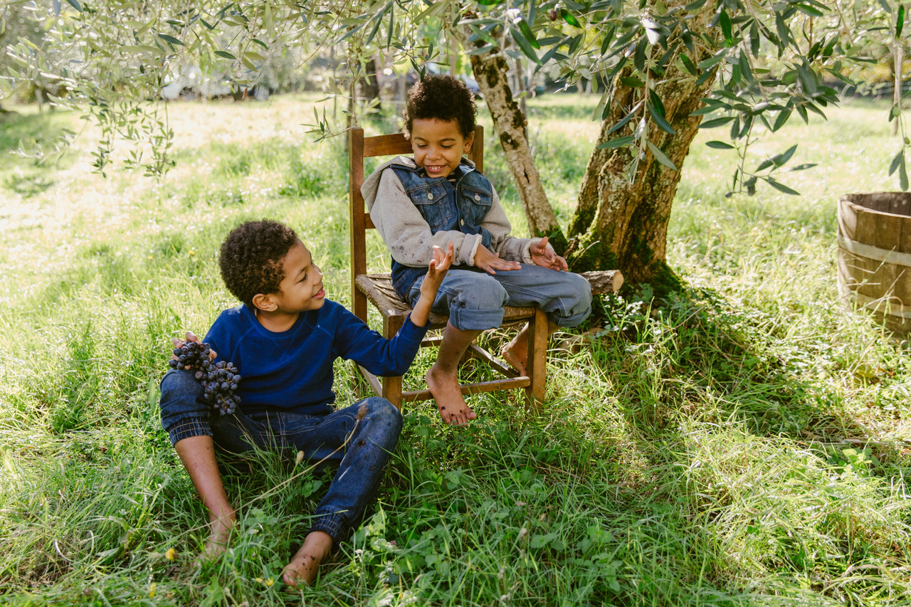 Lifestyle Image by Farhad Samari of two children sitting under a tree with grapes laughing