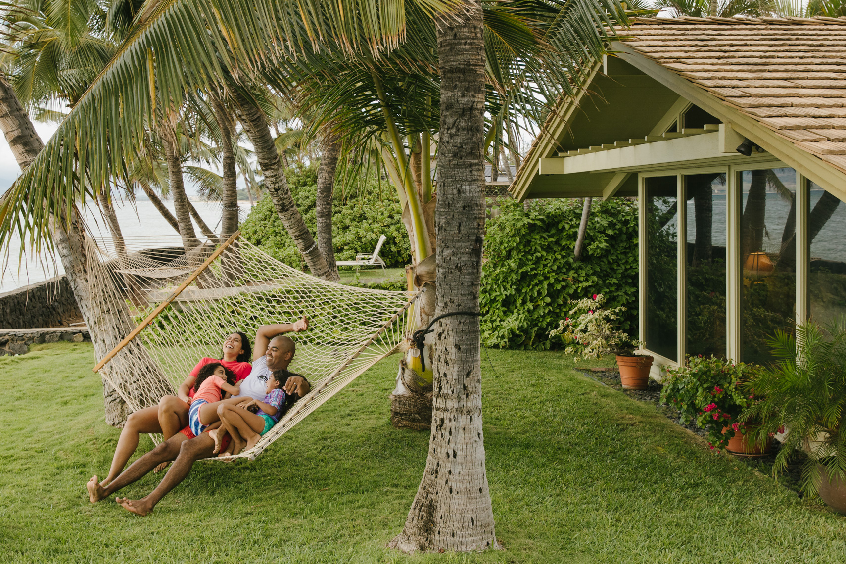 Lifestyle image by SternRep photographer Farhad Samari of a family relaxing and laughing together in a hammock between two palm trees